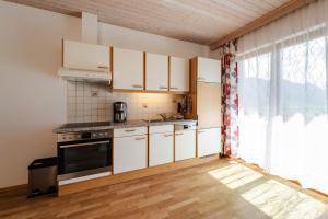 a kitchen with white cabinets and a stove top oven at Ferienhaus Enzi in Weissbriach
