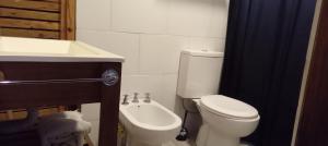 a bathroom with a white toilet and a sink at Días y flores in Ranchos +6 photos
