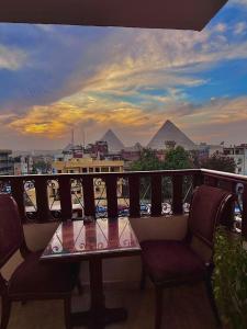 a table and chairs on a balcony with pyramids at Pyramids Art Inn in Cairo