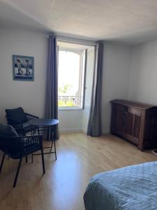 a bedroom with a bed and a table and a window at Ker Lucie in Crozon