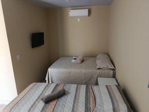 a small room with two beds and a television at Casa Studio Uirá - rua dos Cravos in Chapada dos Guimarães