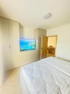 a white bedroom with a bed and a television at J&M apartman in Liptovská Teplá +6 photos