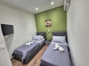 two beds in a small room with green walls at Tommy House CTA in CTA