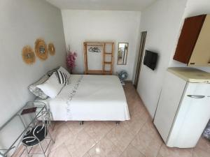 a bedroom with a white bed and a refrigerator at Solares Boa Estada in Búzios