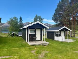 a small house with a porch on a grass field at Mørsvikbotn Camping AS in Mørsvik