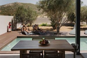 Zwei Personen sitzen auf Stühlen neben einem Pool in der Unterkunft Mitos Ultimate Escape Villa in Galanádhon