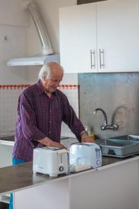an older man standing in a kitchen preparing food at GarçaView in Vila Franca do Campo