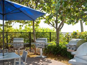 a picnic table with a grill and a blue umbrella at Ocean Pointe Resort One-Bedroom Villa in Palm Beach Shores