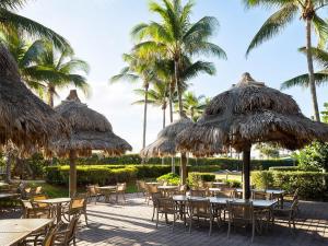 a group of tables and chairs with straw umbrellas at Ocean Pointe Resort Two-Bedroom Villa in Palm Beach Shores