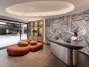 a woman sitting at a desk in a lobby at TRIBE Auckland in Auckland