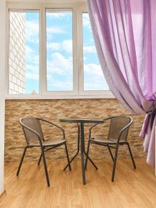 two chairs and a table in a room with windows at Apartment Ekaterina in Chornomorsk