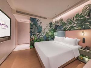 a bedroom with a large white bed and a plant wall at Mercure Xishuangbanna in Jinghong +68 photos