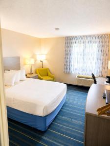 a hotel room with a bed and a yellow chair at Days Inn by Wyndham Hinckley in Hinckley +52 photos