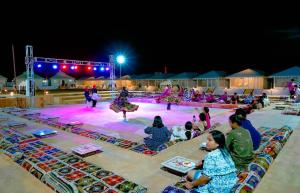 a group of people watching a performance at night at Royal Salma Resort A family Luxury Camp  +39 photos