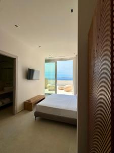 a bedroom with a bed and a view of the ocean at Fenici Levanzo Hotel - Adults Only in Levanzo