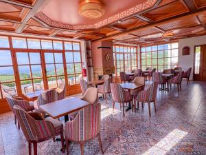a dining room with tables and chairs and windows at Oussoul House in Feddane Saïdi