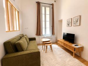 a living room with a green couch and a television at Cosy-T2 - Hyper centre Montpellier in Montpellier