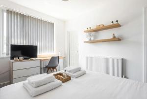 a white room with a bed and a desk and a television at Doncaster Budget Room in Shared House w Kitchen in Doncaster +8 photos