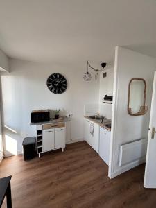 a kitchen with white cabinets and a clock on the wall at Saint Hilaire sea view accommodation in Saint-Hilaire-de-Riez