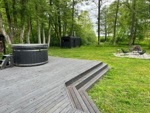 a wooden deck with a trash can on top of a park at Ziemupes namiņš in Ziemupe +6 photos