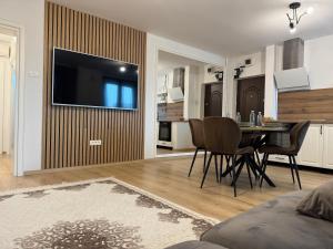 ein Wohnzimmer mit einem Tisch und einem Fernseher an der Wand in der Unterkunft Avenue in Arad