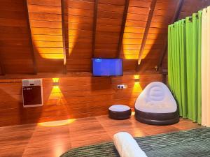 a room with a tv and a chair in a room at Rainforest Emerald Haven in Deniyaya