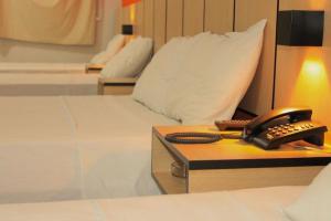 a room with two beds and a phone on a desk at Hotel JCA Uberlândia in Uberlândia