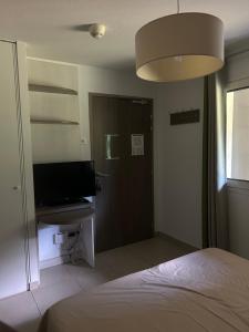 a bedroom with a bed and a door with a television at Le petit studio du Gard in Remoulins