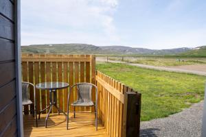 a patio with a table and chairs on a deck at Hvammur 6 with private hot tub in Hafnarhólmur