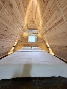 a large bed in a wooden room with a window at KolsayNestAframe in Saty