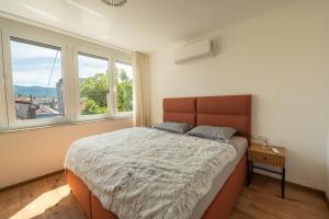 a bedroom with a large bed and two windows at Apartment Center Korzo 2 in Bihać