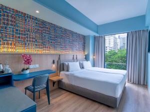 a hotel room with a bed and a desk and a window at ibis Styles Kuala Lumpur Bukit Bintang in Kuala Lumpur