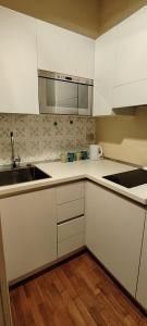 a kitchen with white cabinets and a sink at Casa Becci Central Bright & Cozy Flat in San Gimignano