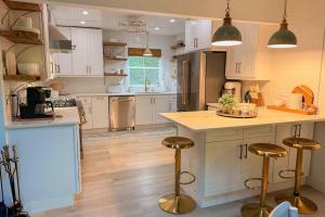 a kitchen with white cabinets and a island with bar stools at Dragonfly Cabin in Scaly Mountain +33 photos