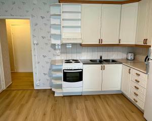 a kitchen with white cabinets and a stove and a sink at Spacious one room apartment in Vaasa +1 photo