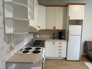 a kitchen with white cabinets and a white refrigerator at Spacious one room apartment in Vaasa