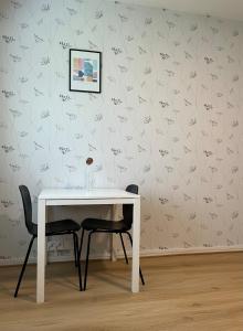 a white table with two chairs in front of a wall at Spacious one room apartment in Vaasa