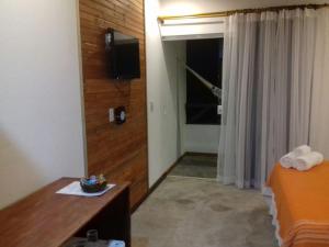 a hotel room with a bed and a door with a television at Pousada Barra Trip in Barra Grande
