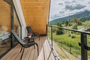 a balcony with two chairs and a table and a view at Domki Tymianek & Melisa in Kościelisko