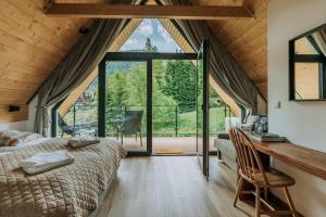 a bedroom with a bed and a large window at Domki Tymianek & Melisa in Kościelisko