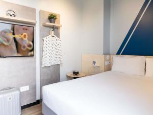 a bedroom with a white bed and a painting on the wall at ibis budget Madrid Albasanz in Madrid