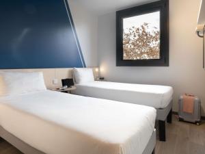 two beds in a hotel room with a window at ibis budget Madrid Albasanz in Madrid +53 photos