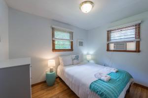 a bedroom with a white bed and two windows at Beach House with Spacious Deck for Entertaining in Narragansett