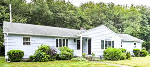 a white house with trees in the background at Beach House with Spacious Deck for Entertaining in Narragansett