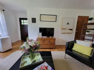 a living room with a tv and a vase of flowers at Beach House with Spacious Deck for Entertaining in Narragansett