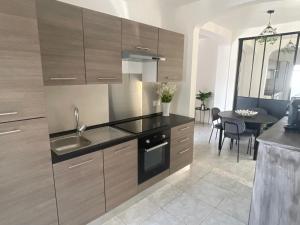a kitchen with wooden cabinets and a dining room at Appart dans bâtisse provençale in Sorgues