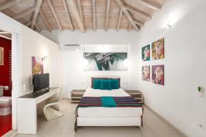 a white bedroom with a bed and a television at Skiathos Garden Cottages in Skiathos