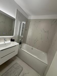 a white bathroom with a sink and a tub and a mirror at Urban Elegance in Cluj-Napoca +13 photos