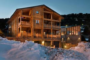 een groot houten huis met sneeuw ervoor bij 4YOULODGE in Les Angles