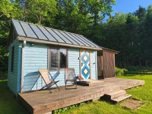 two chairs on a wooden deck in front of a tiny house at Private tinyhouse - Blue House in Lõupõllu